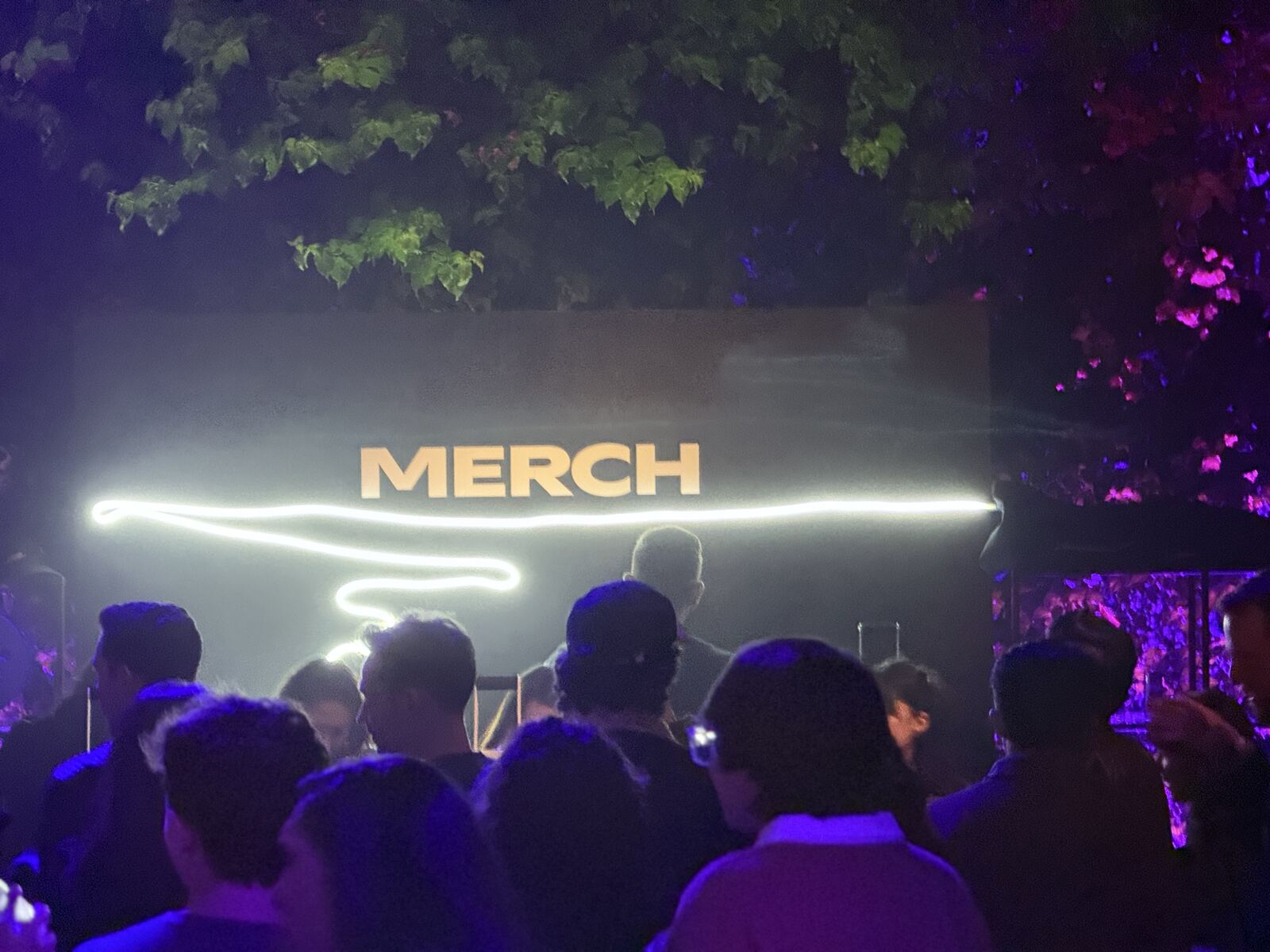 Event floor view showing the hat bar booth and merchandise displays with a crowd of guests