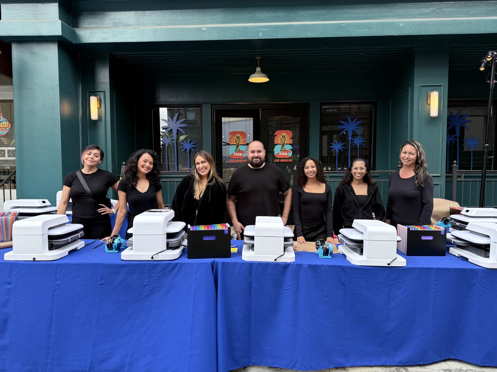 Team at an event booth with printing equipment and a decorated merchandise table